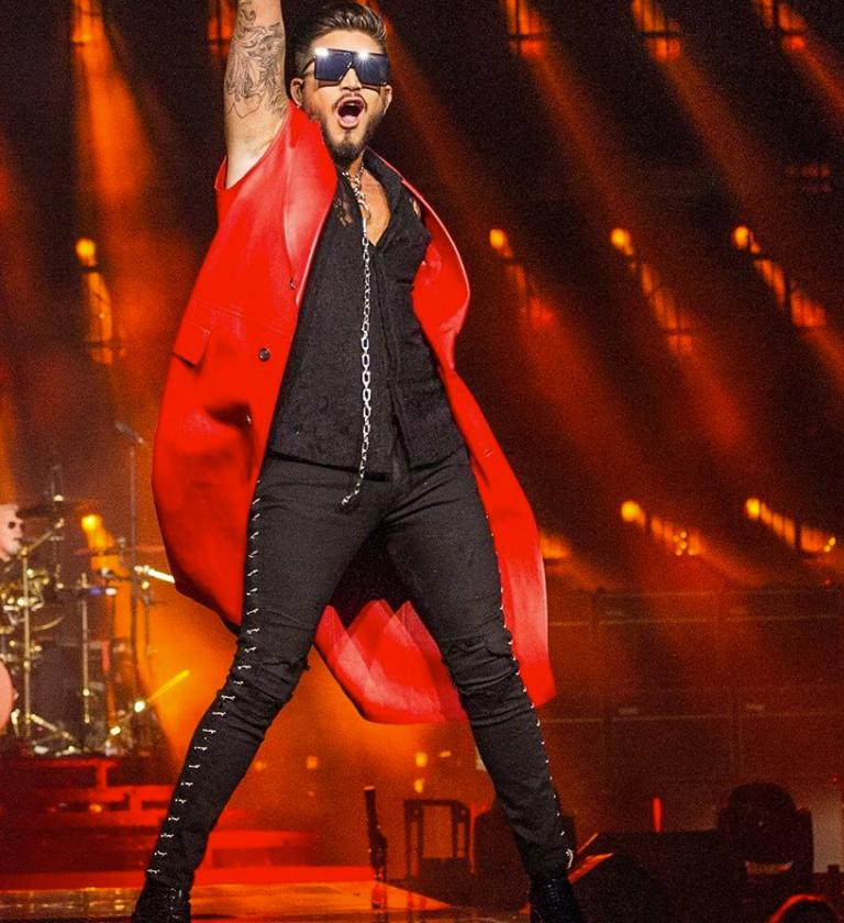Adam Lambert stood on stage with his fist in the air in a triumphant manner