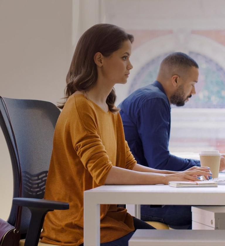 Woman and man both working sat at a desk side by side